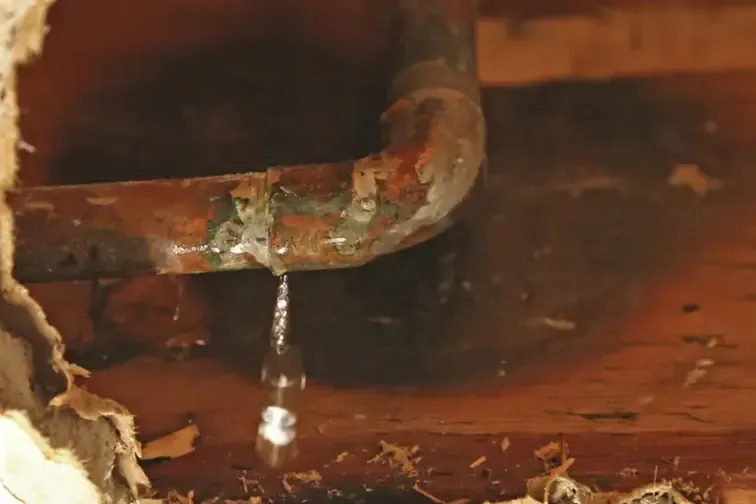 A copper pipe dripping inside an opened wall cavity