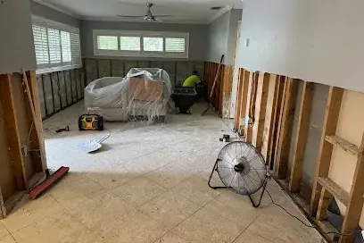 Flood cut walls and a floor fan in a gutted living room