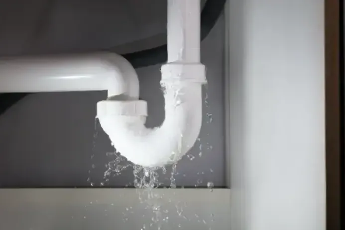Water spraying from a failed pipe joint in the cabinet under a sink