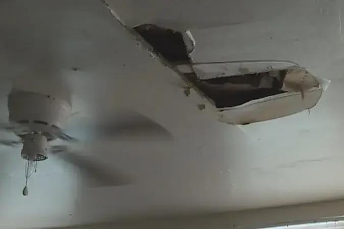 A ceiling cut open around a light fixture after a leak from the floor above