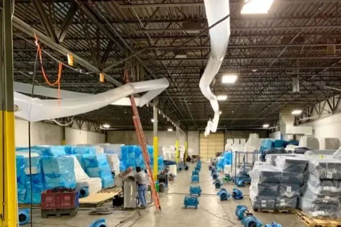Rows of air movers drying the concrete floor of a large warehouse